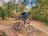 A happy cyclist riding a mountain bike on a forest trail during autumn.