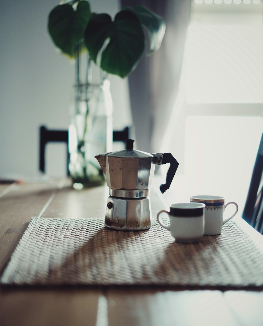 stainless steel teapot beside white ceramic mug on table