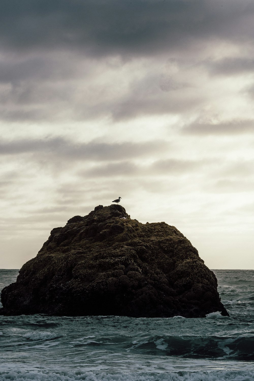 silhouette of person sitting on rock formation during daytime