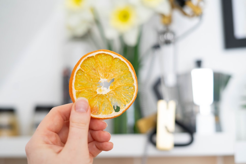 person holding orange fruit in shallow focus lens