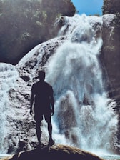 man in black jacket standing near waterfalls
