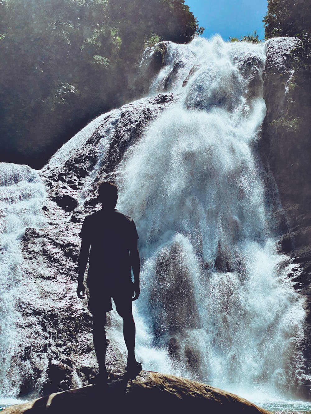 man in black jacket standing near waterfalls