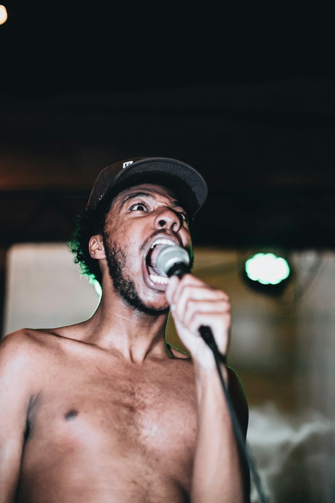 topless man wearing black hat singing