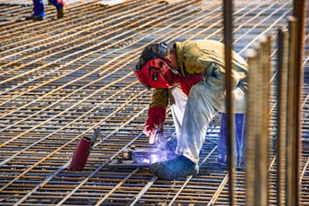 man in yellow shirt and red helmet climbing on brown wooden ladder during daytime