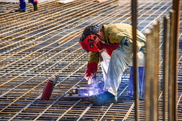 man in yellow shirt and red helmet climbing on brown wooden ladder during daytime