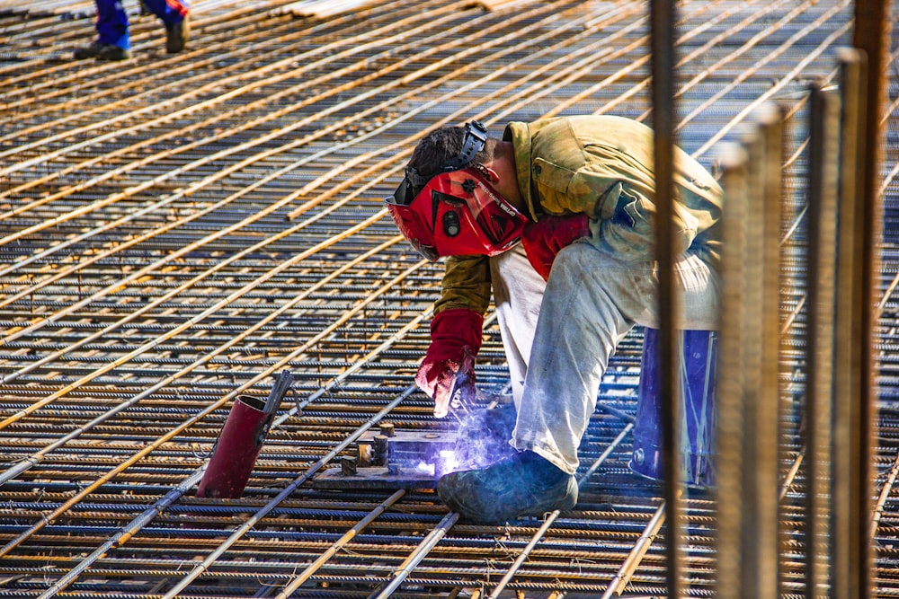 man in yellow shirt and red helmet climbing on brown wooden ladder during daytime