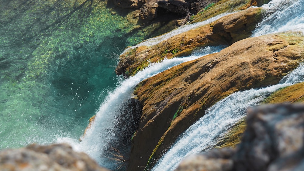 water falls on brown rocky mountain during daytime