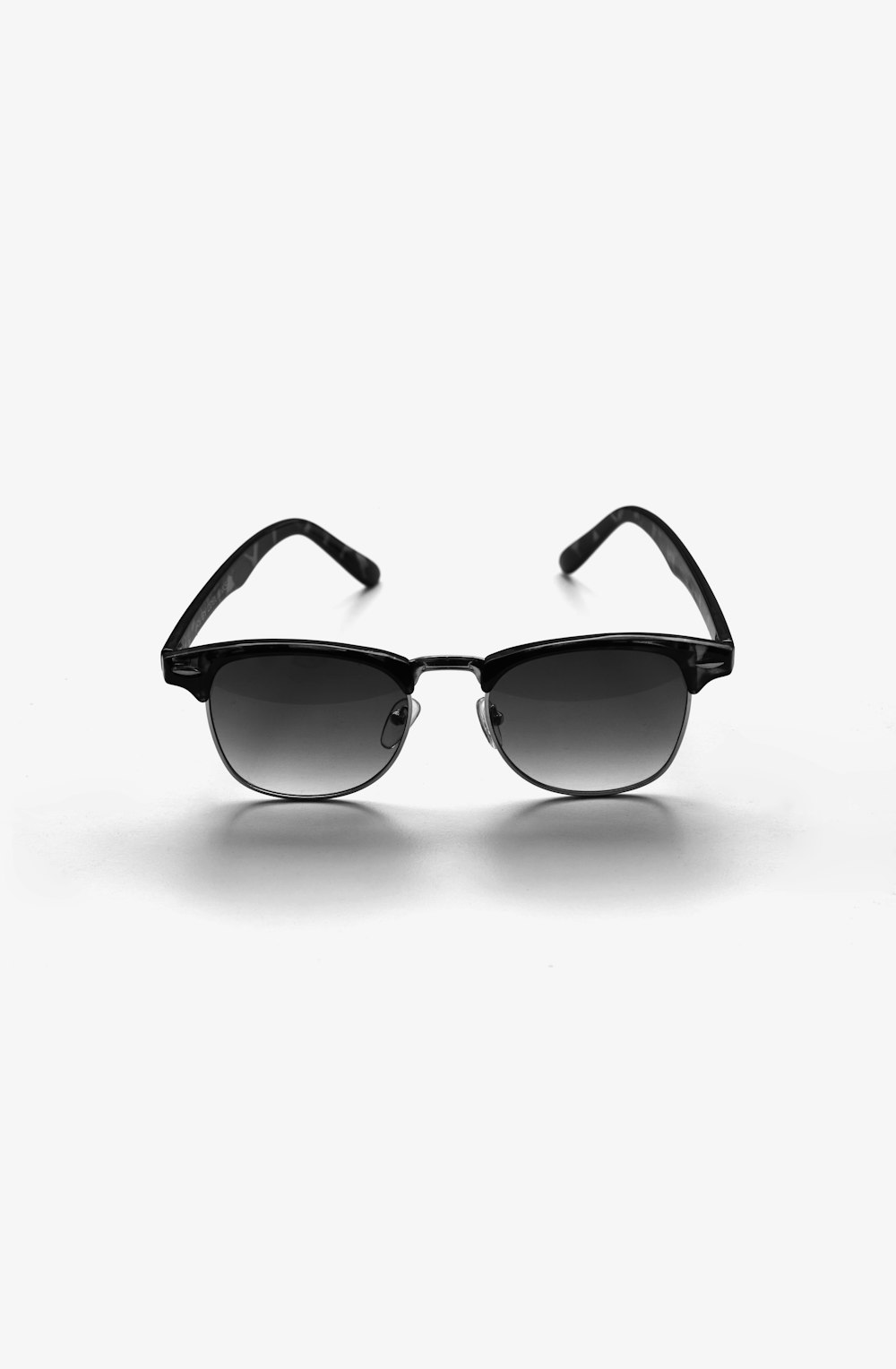 Lunettes de soleil à monture noire sur surface blanche