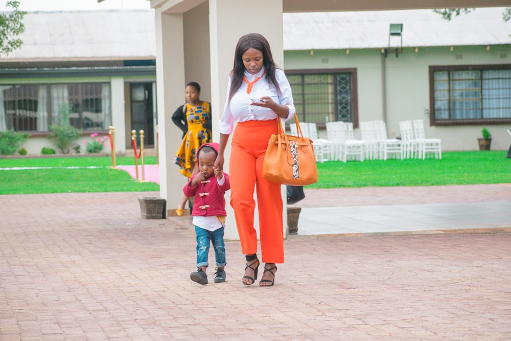 2 women in white and orange long sleeve shirt and blue denim jeans standing on brown