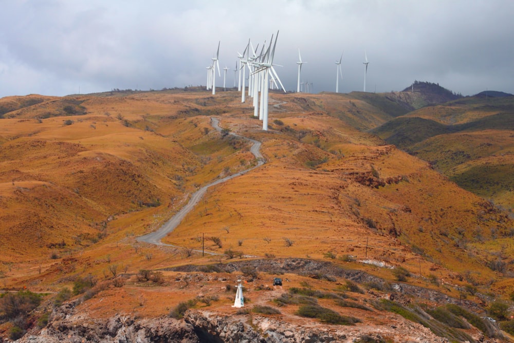 turbine eoliche bianche su campo marrone sotto cielo nuvoloso bianco durante il giorno