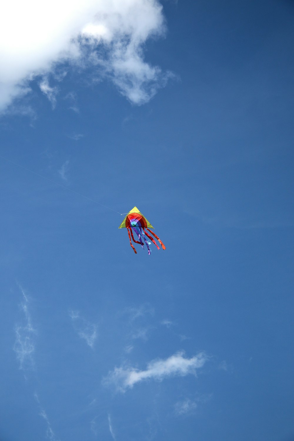 yellow red and blue kite flying under blue sky during daytime