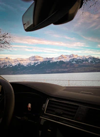 Interior shot of a premium car showing plush leather seats and a scenic mountain view through the window.