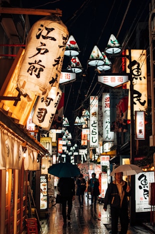 A vibrant street scene in Tokyo with colorful lanterns and bustling crowds at dusk.