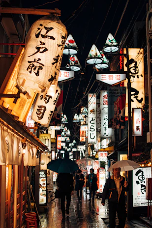 A vibrant street scene in Tokyo with colorful lanterns and bustling crowds at dusk.