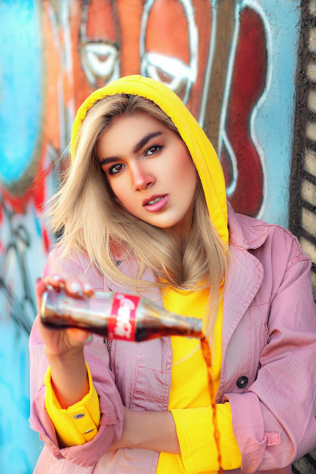 woman in yellow hijab and brown coat holding bottle