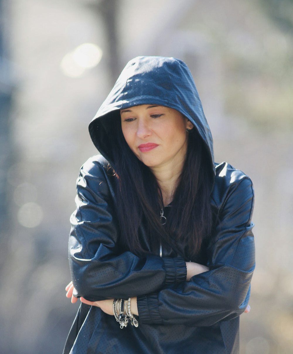 a woman wearing a black jacket and a hoodie