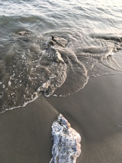 A gentle wave washing over smooth sea glass fragments on a rocky shore