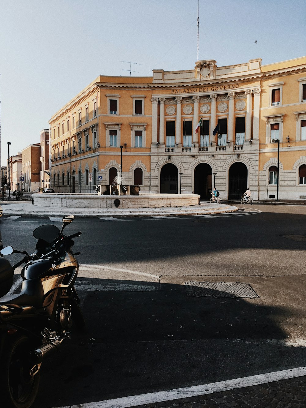 black motorcycle parked beside brown concrete building during daytime