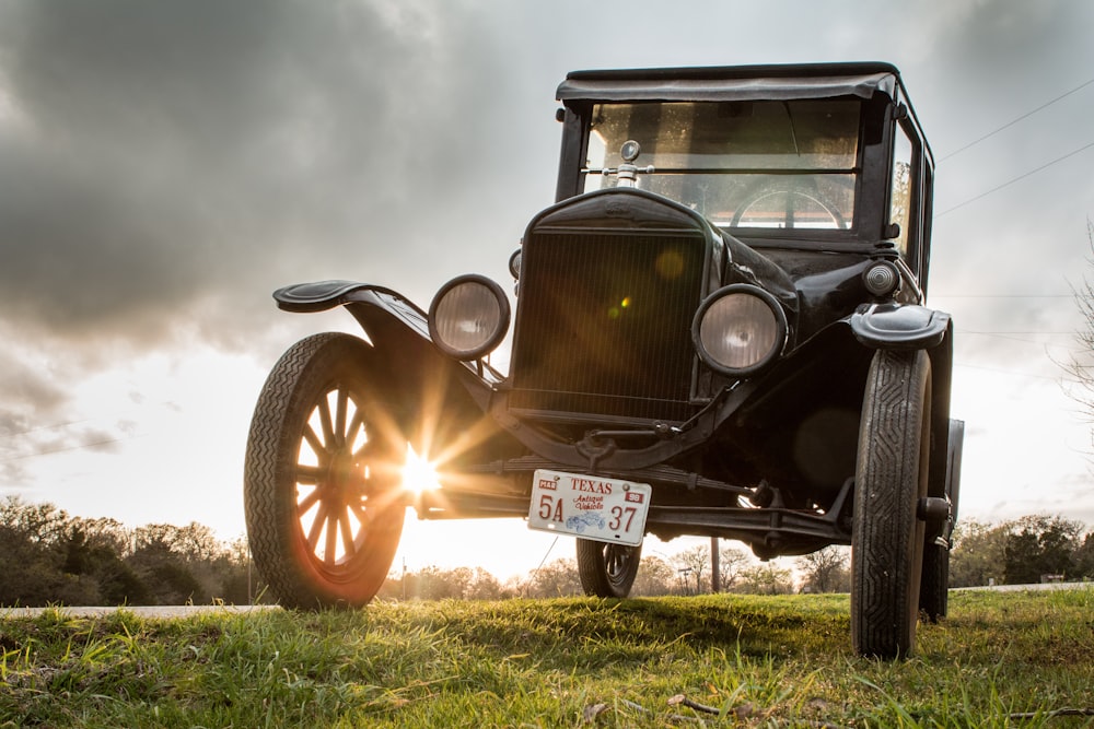 vintage black car on green grass field under cloudy sky during daytime