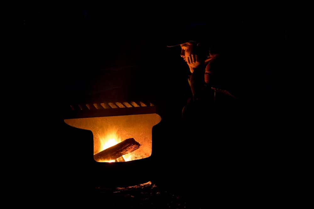 焚き火台のそばに立つ帽子をかぶった男のシルエット