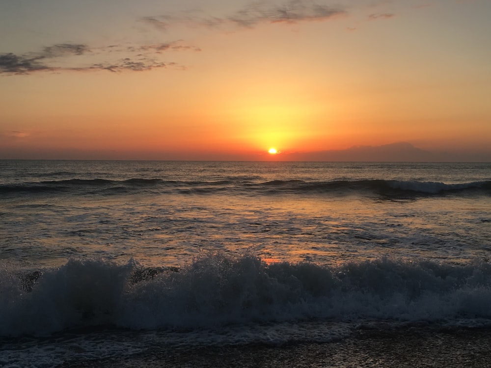 sea waves crashing on shore during sunset