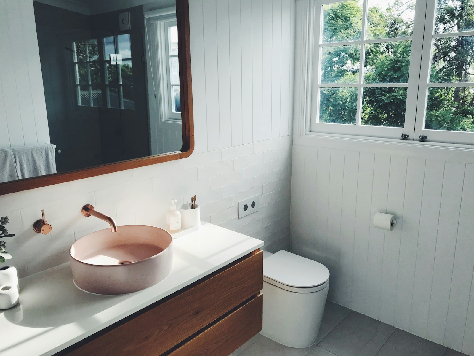 small bathroom with pink basin sink wood vanity and round mirror
