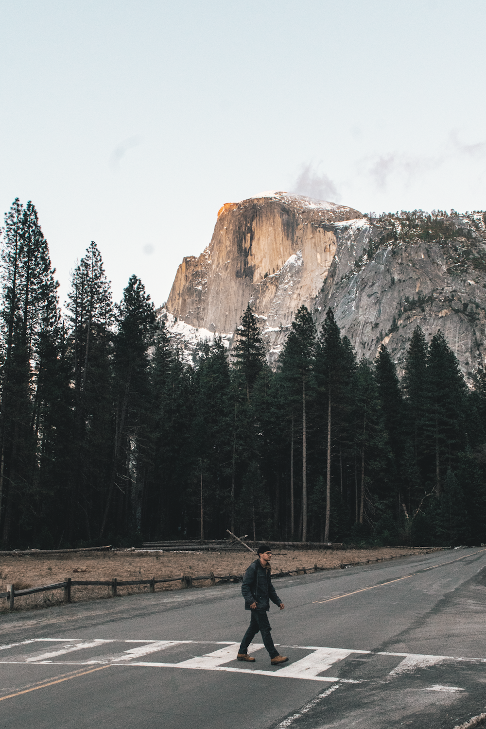 person in black jacket walking on gray asphalt road during daytime