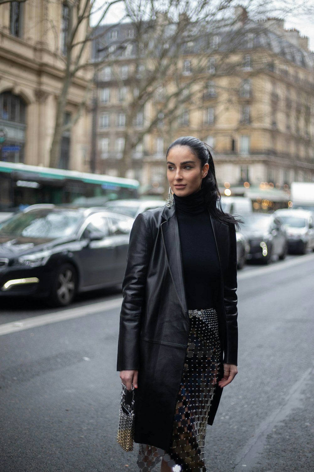 mulher na jaqueta de couro preta que está na calçada durante o dia