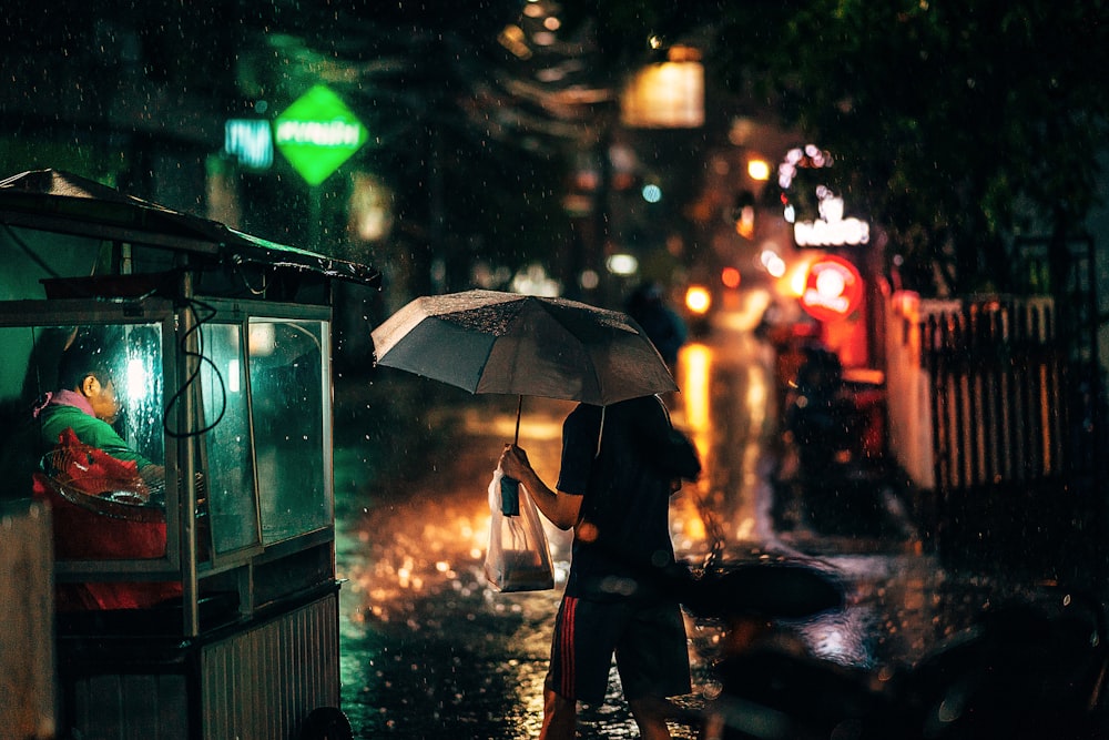 woman in black coat holding umbrella during night time