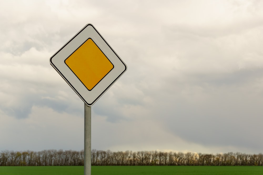 yellow and white road sign under cloudy sky during daytime