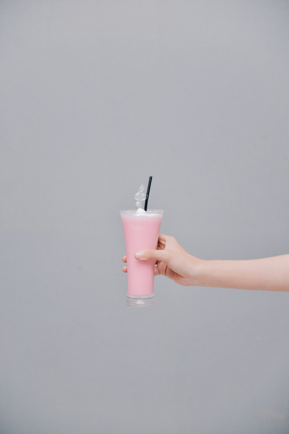 person holding pink liquid in clear drinking glass