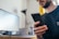 A close-up of a person checking their phone for delivery updates while sitting at a desk.