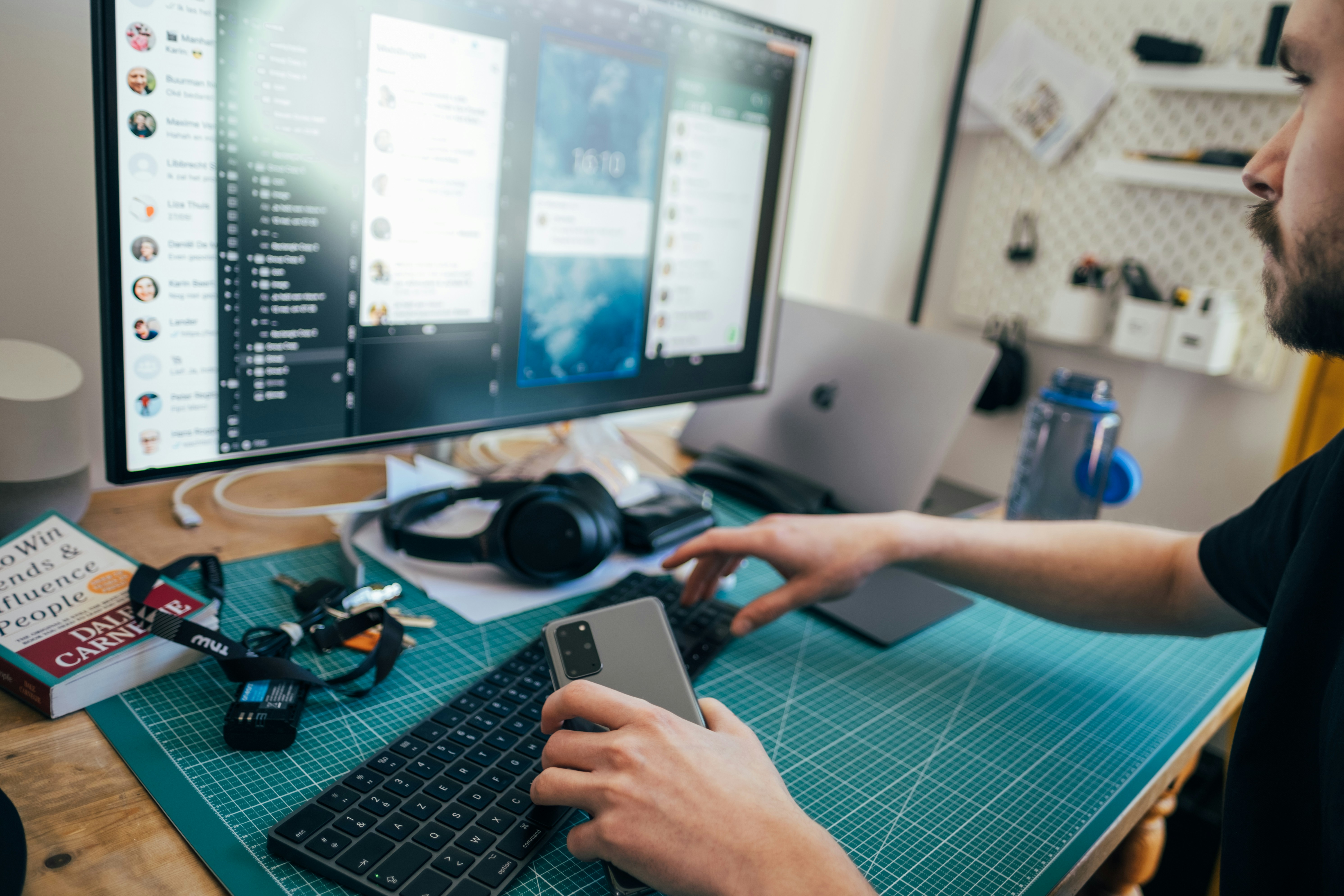 Young man holding phone in his hands at a desk. Picture taken by Jonas Leupe (www.brandstof.studio) for Tandem Tech (www.tandemtech.be)