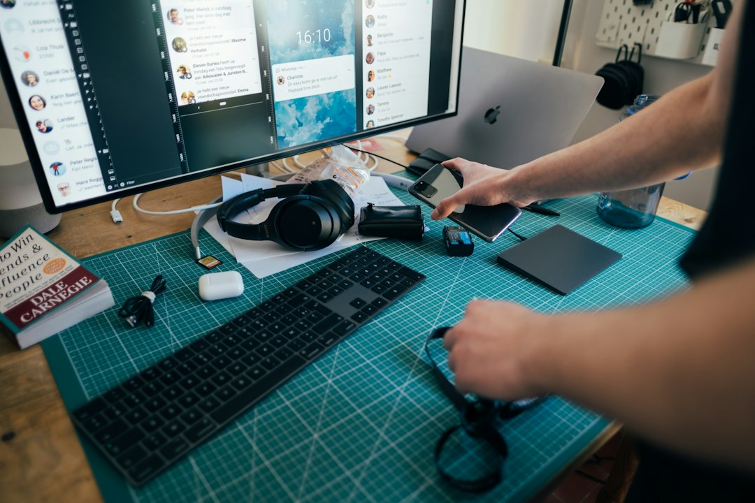 Young man holding phone in his hands at a desk. Picture taken by Jonas Leupe (www.brandstof.studio) for Tandem Tech (www.tandemtech.be)