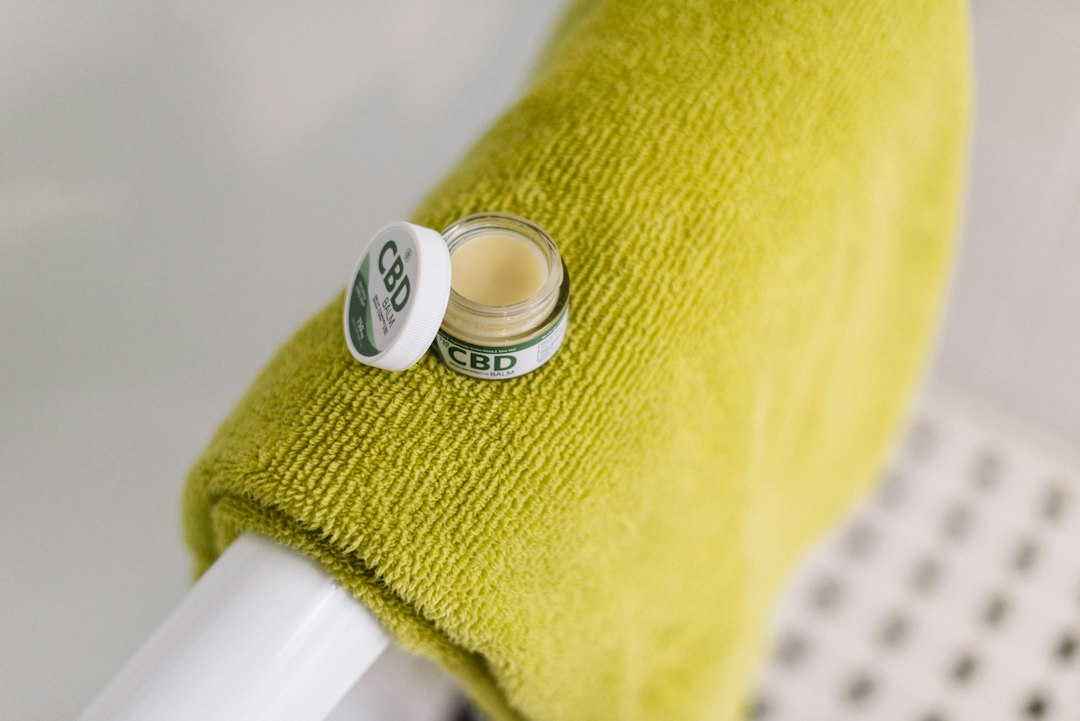 white round plastic container on yellow textile, Hempure CBD balm.