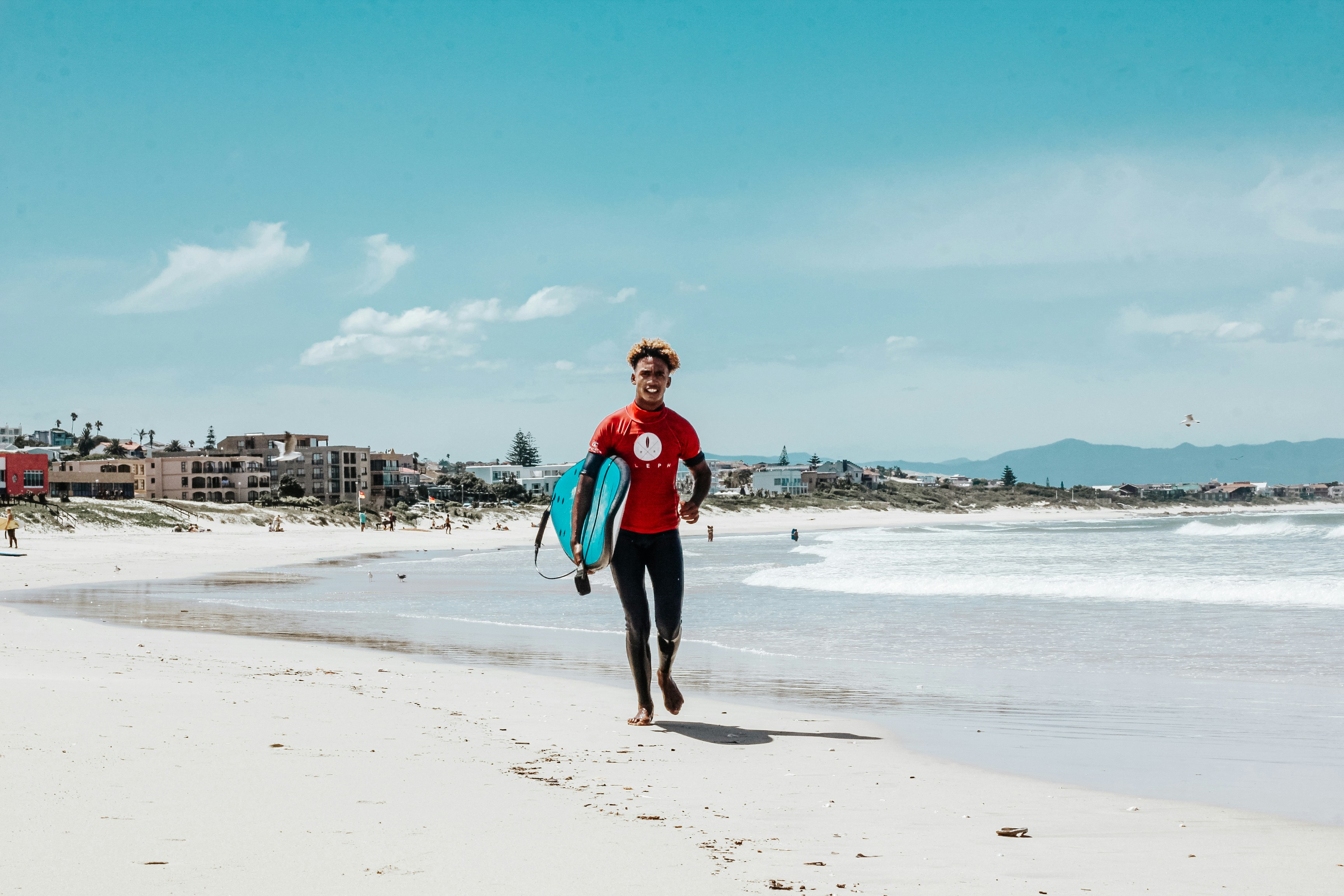 woman in red jacket and black shorts standing on beach during daytime