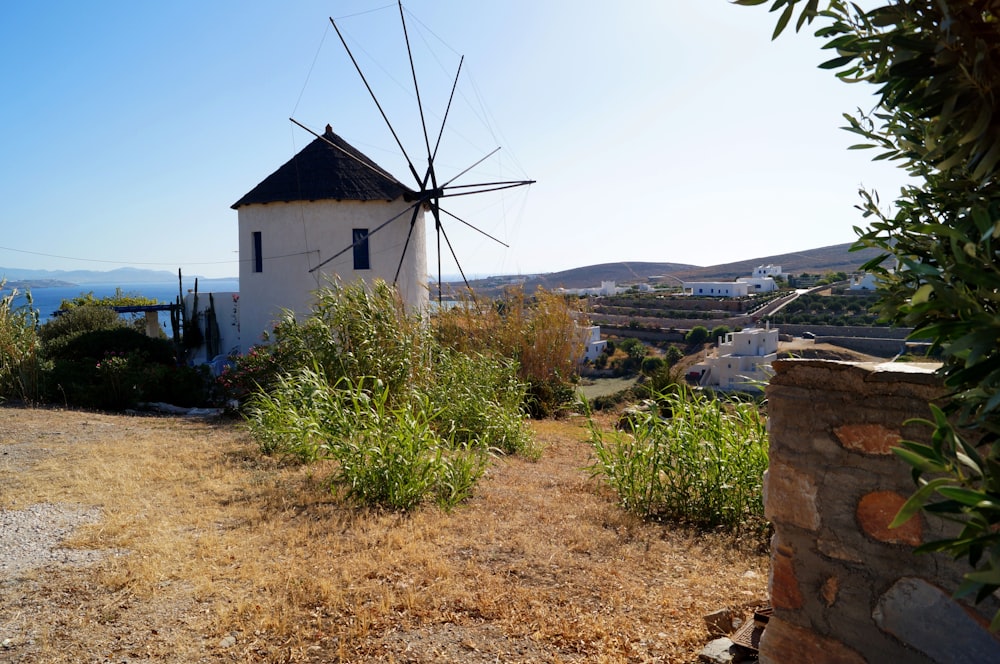 white and brown windmill near green trees during daytime