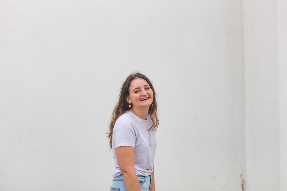 woman in white crew neck t-shirt and blue denim shorts smiling