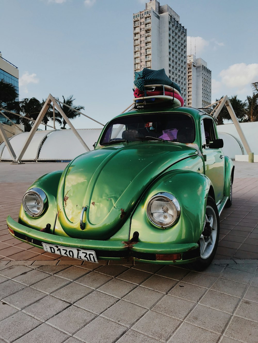green volkswagen beetle parked on brown brick floor during daytime