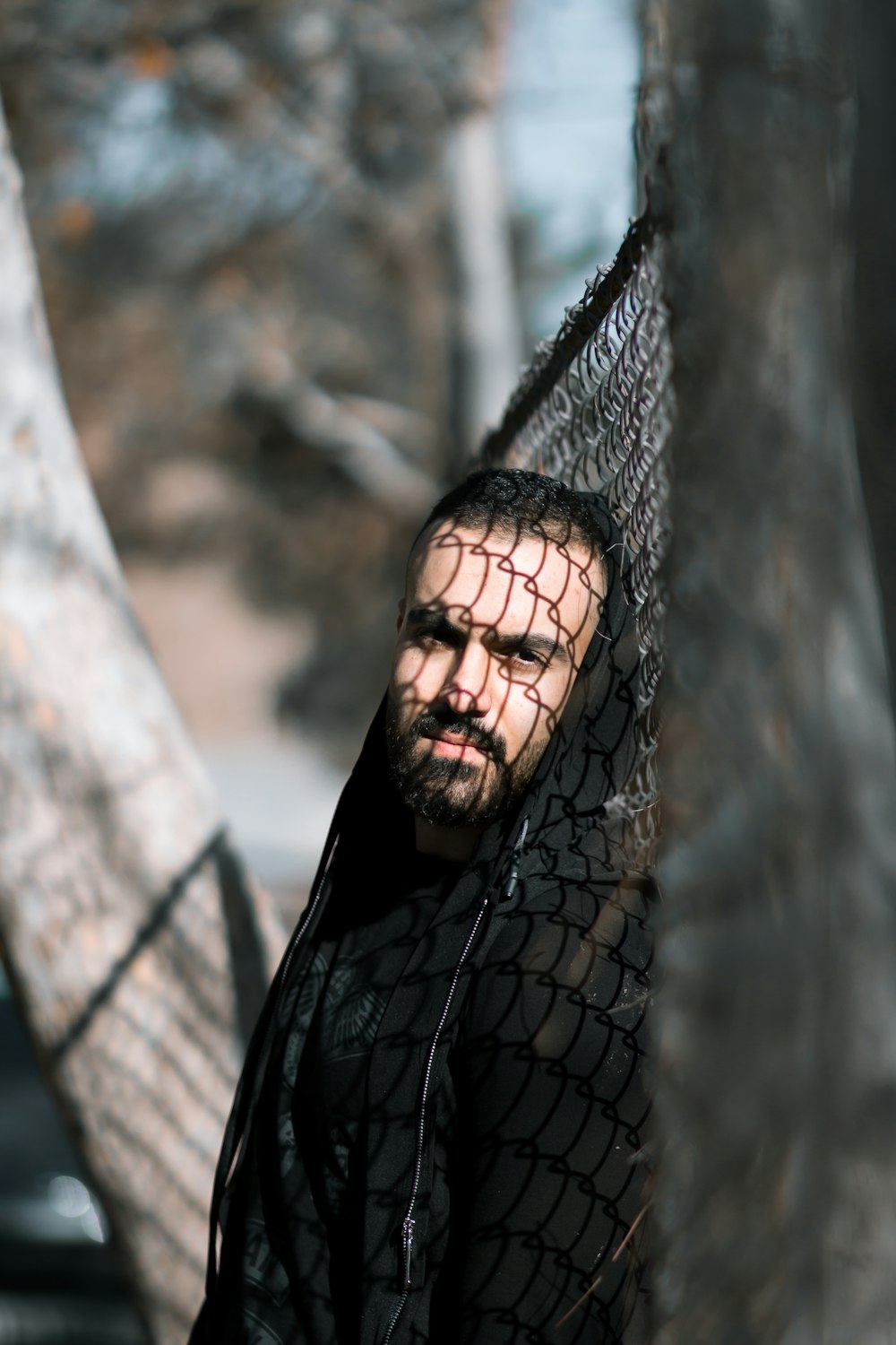 man in black jacket standing behind gray net