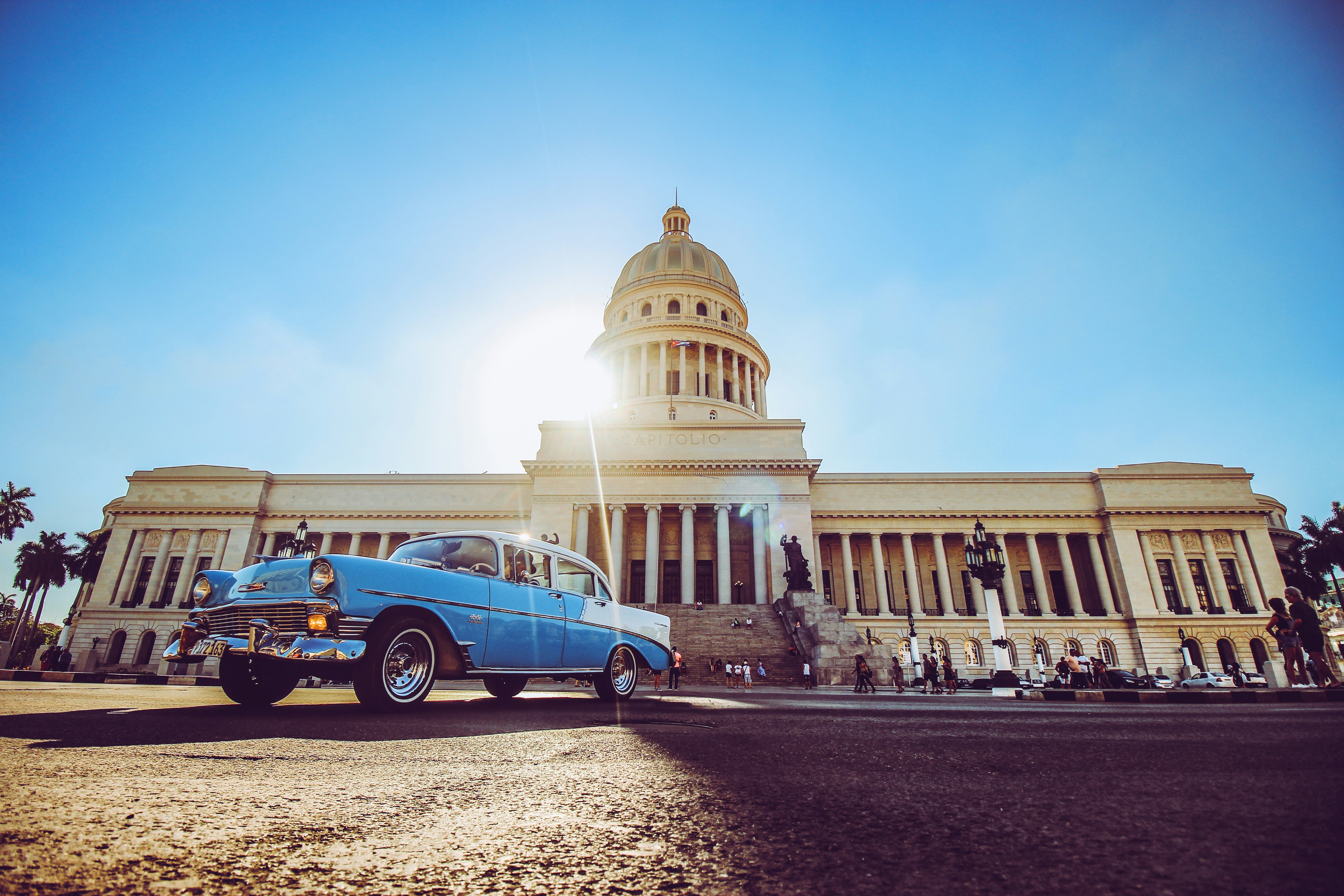 blue and white volkswagen beetle parked near white concrete building during daytime