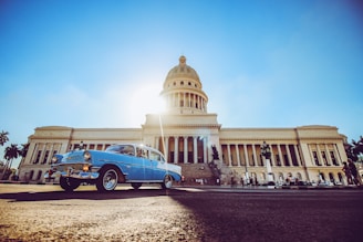 blue and white volkswagen beetle parked near white concrete building during daytime