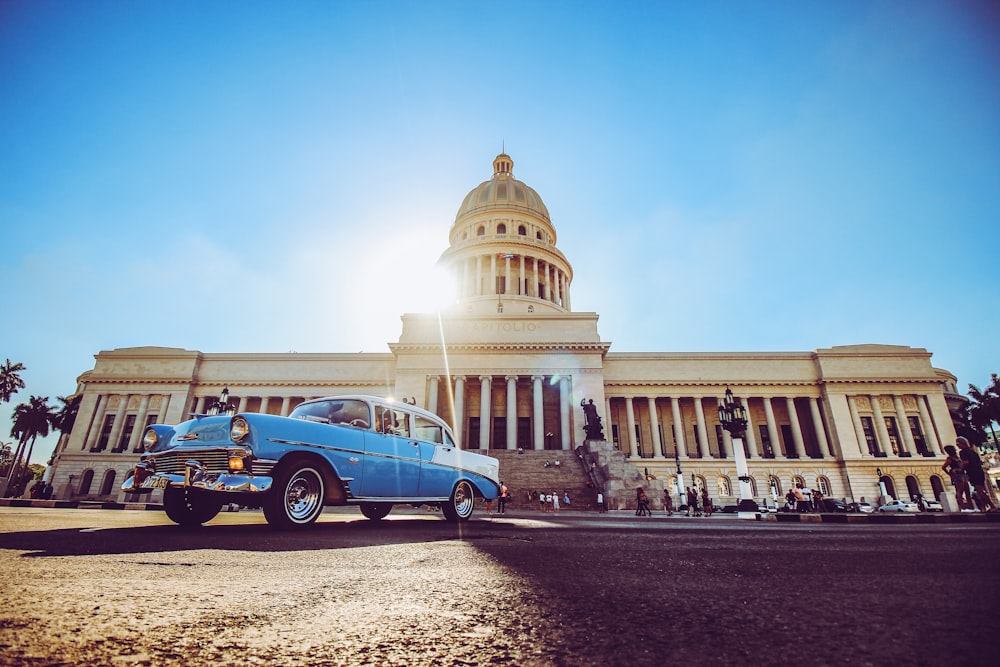 blue and white volkswagen beetle parked near white concrete building during daytime