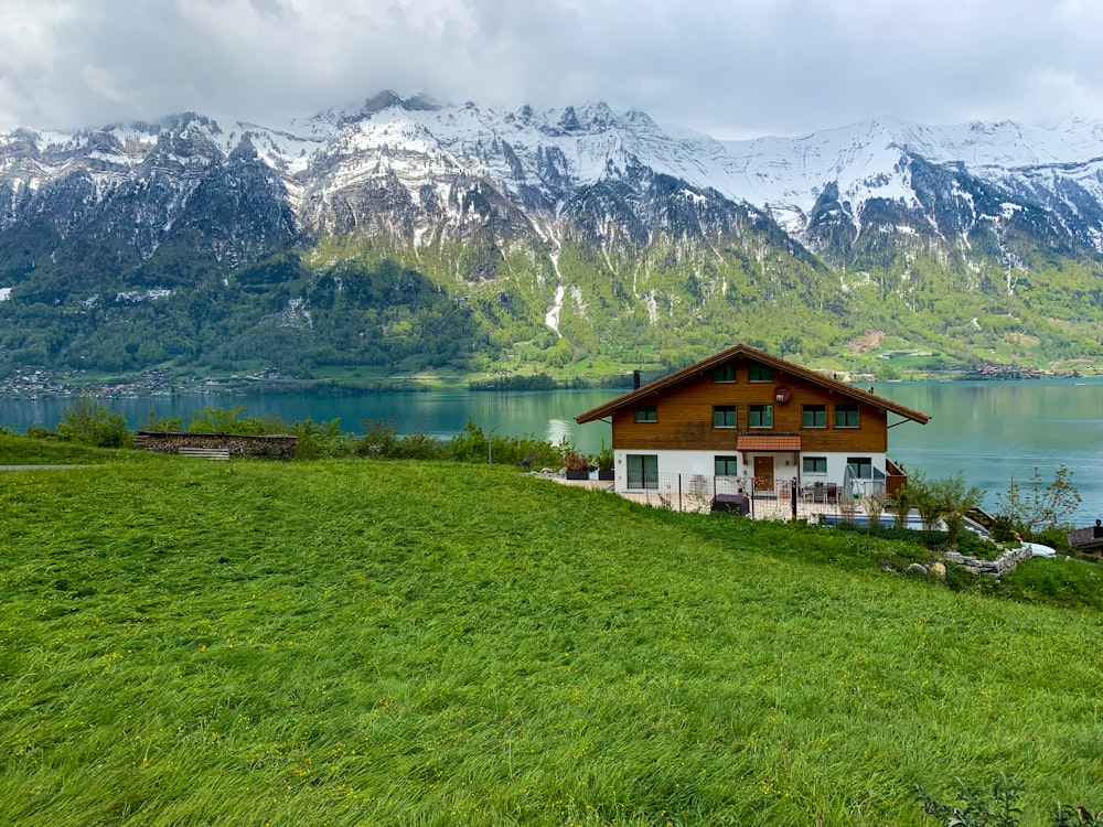 Casa blanca y marrón cerca de campo de hierba verde y montaña durante el día