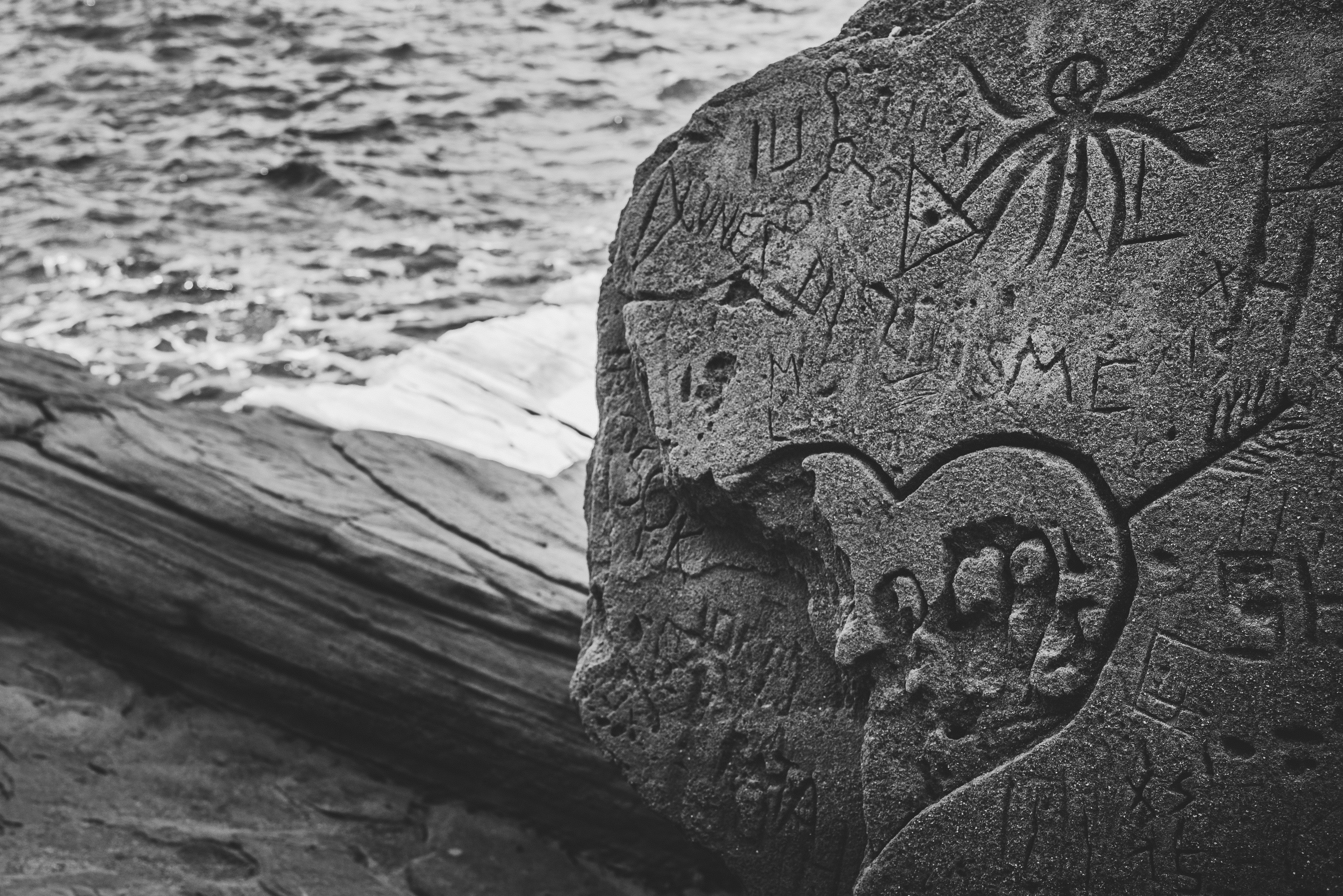 Black & white stone carvings on a rock by the sea