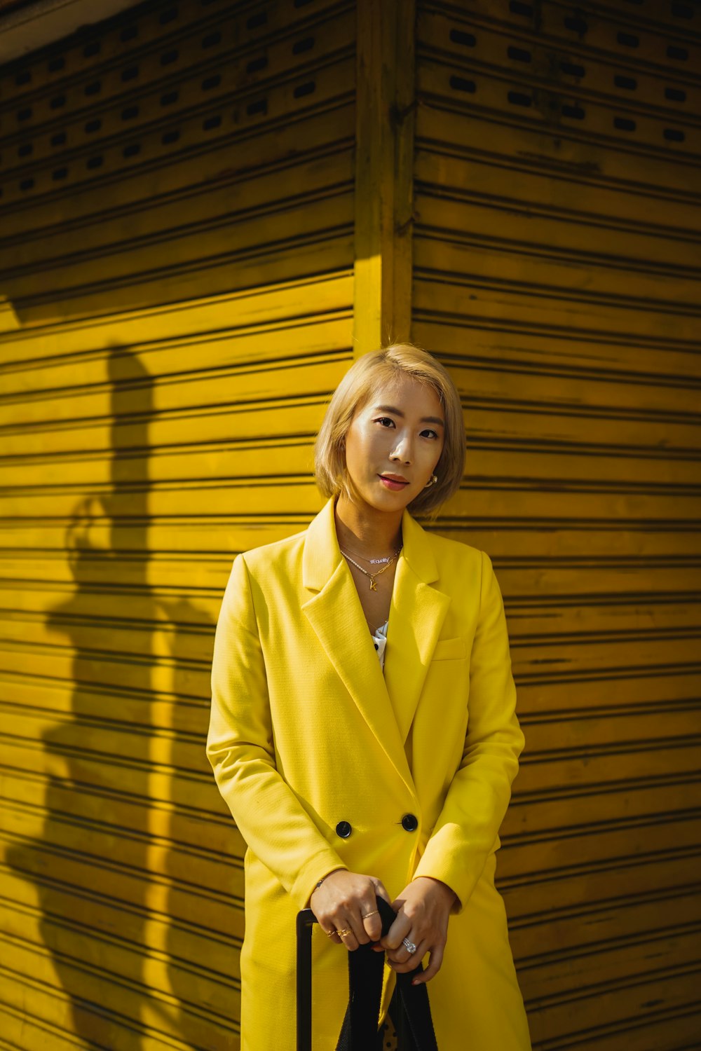 woman in yellow blazer standing beside yellow wooden wall