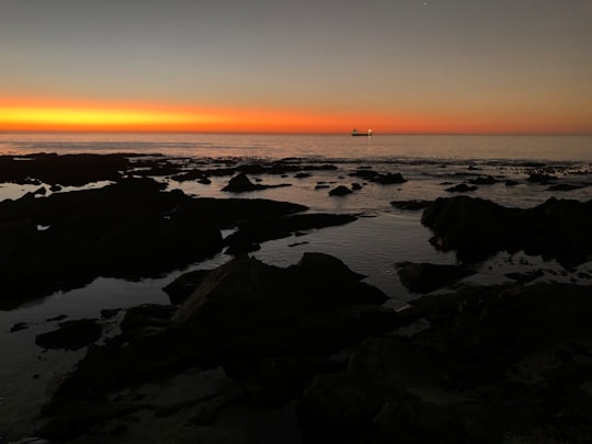 black rocks on sea shore during sunset in Sea Point South Africa