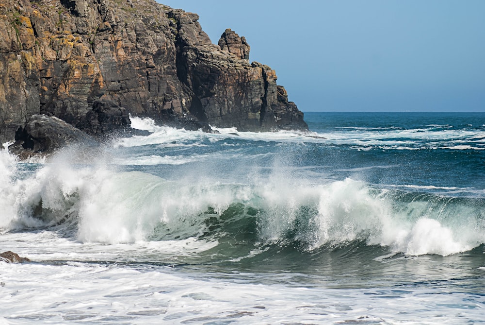 ocean waves crashing on brown rock formation during daytime