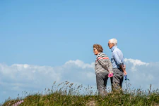 man in white dress shirt and black pants standing beside woman in black and white striped