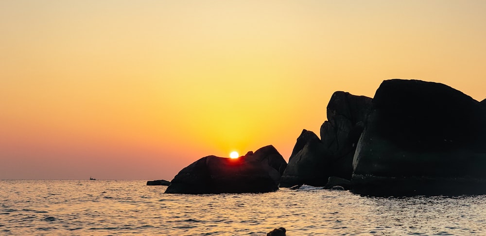 rock formation on body of water during sunset